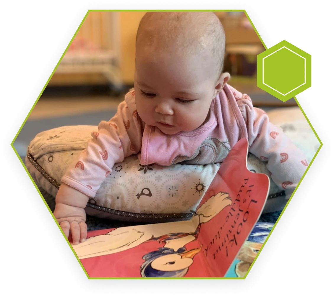 A baby is reading a book on the floor.