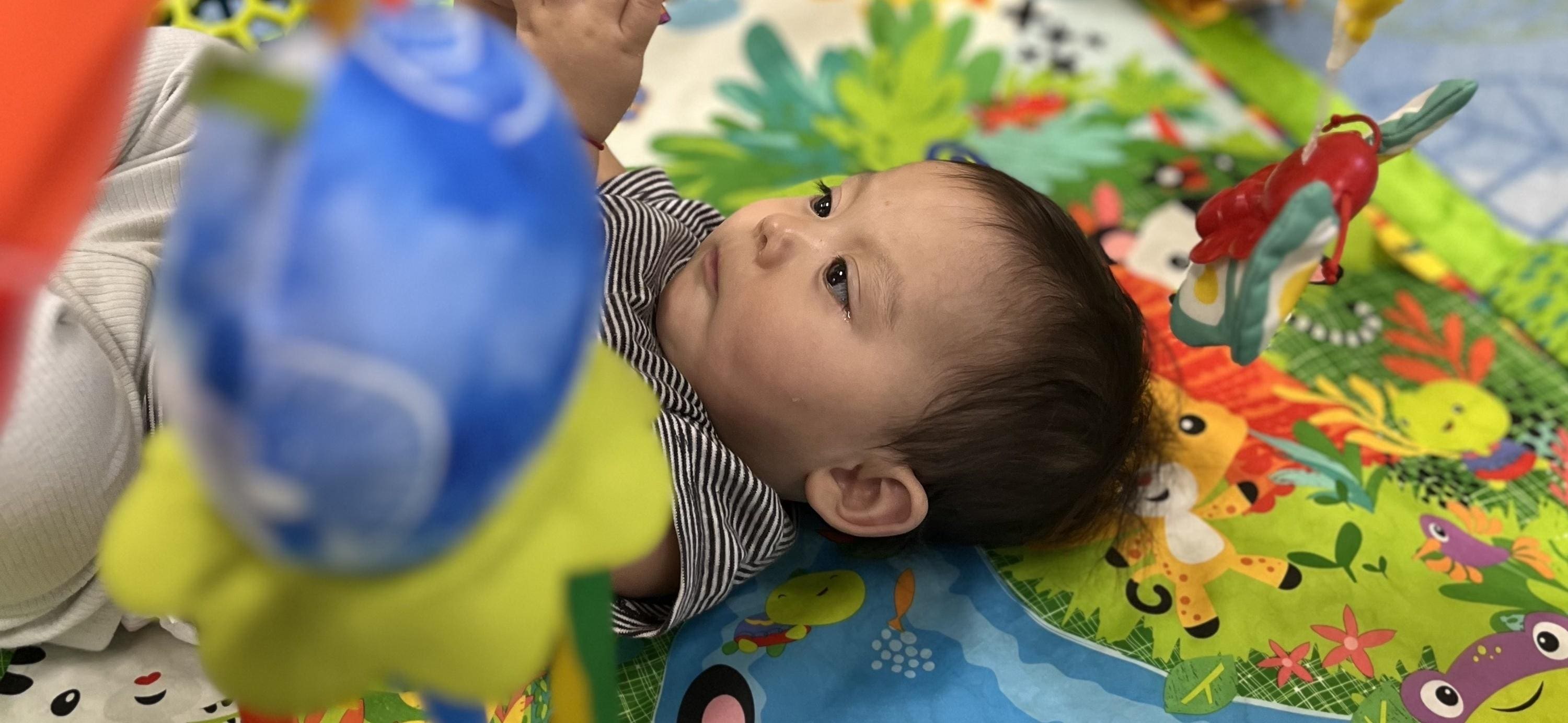 A baby is laying on the ground with his head up.