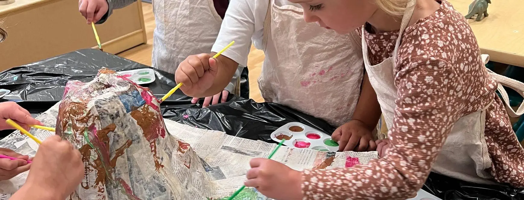 A group of people painting on paper with paint brushes.