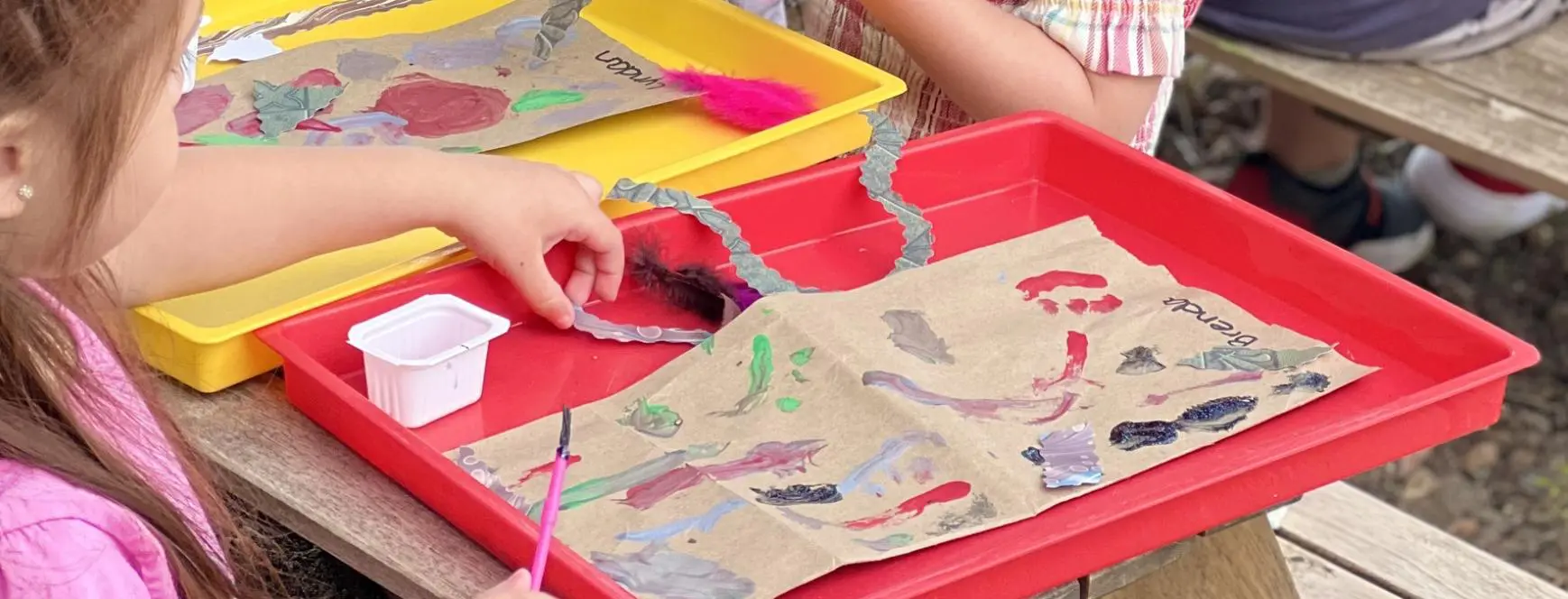 A child is making paper bags with scissors and glue.