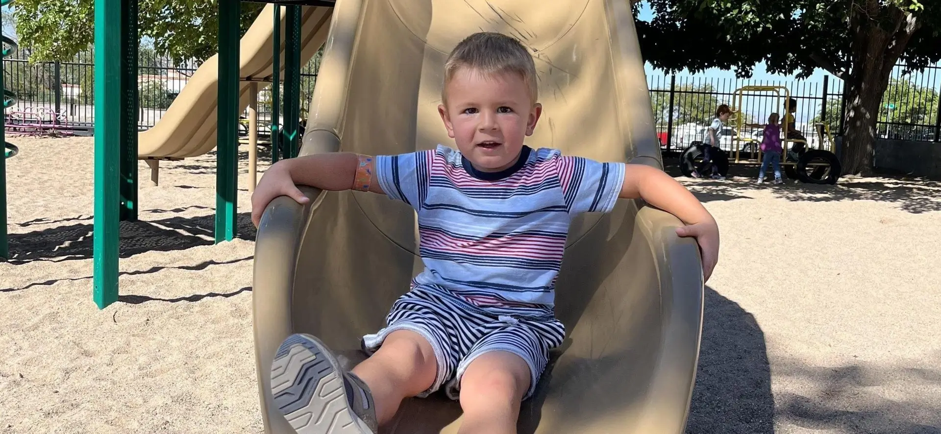 A young boy sitting on top of a slide.